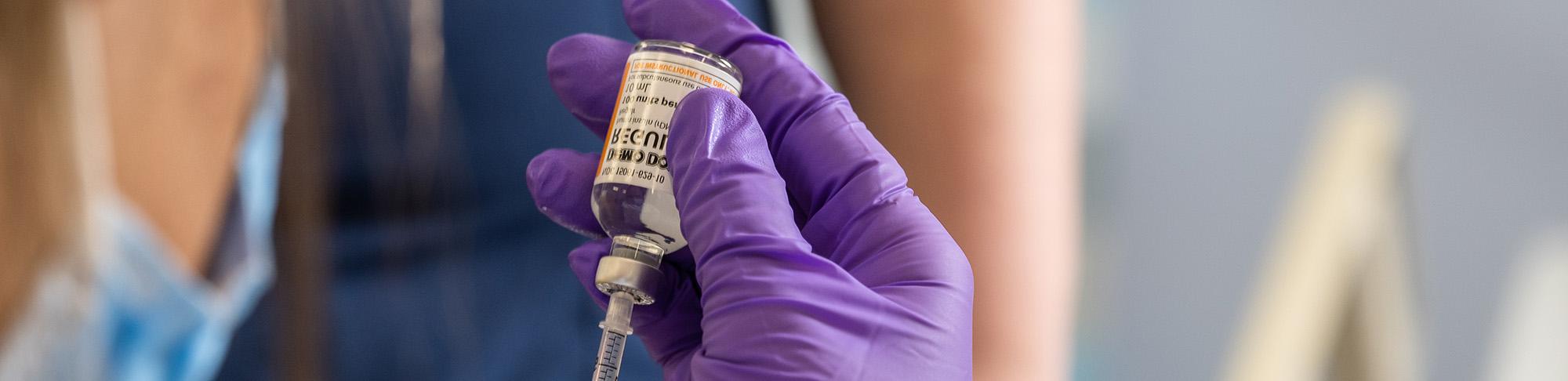 Nurse using syringe to draw medication from a vial