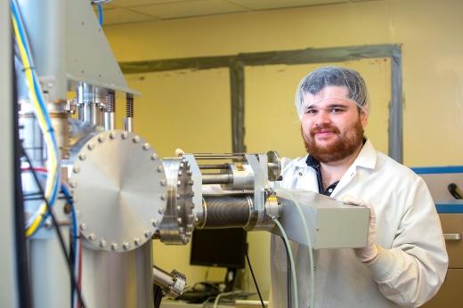 Student in a lab standing behind large power tool