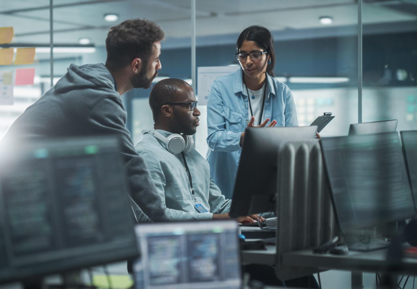 Woman and two men discuss something in computer lab