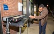 A student points a thermometer at a screen-printing machine.