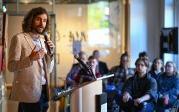 A man speaks into a microphone in front of a group of people.