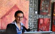 A woman speaks into a microphone at a podium.