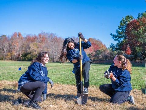 three female odu students dig a hole to plant a tree